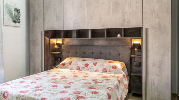 A bedroom with a bed, a headboard with built-in shelves, and wall-mounted reading lights. - La Capinera by Wonderful Italy (Noto)