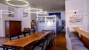 A dining area with a wooden table and chairs, pendant lights, a bookshelf, and a cabinet. - Country house Wendy 1 semi-detached house 250 m² 6 bedrooms, 4 bathrooms, garden (Gägelow)