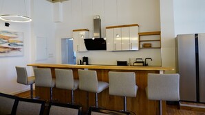 A modern kitchen with a bar area, white cabinetry, and a stainless steel refrigerator. - Country house Wendy 1 semi-detached house 250 m² 6 bedrooms, 4 bathrooms, garden (Gägelow)