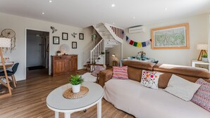 Un salon moderne avec un escalier, un plancher en bois, un canapé, une table basse et un coin repas.