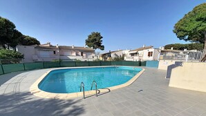 A swimming pool with a tiled deck, surrounded by buildings and trees. - LA PINEDA 200m from the naturist village with parking space and swimming pool (Occitanie)