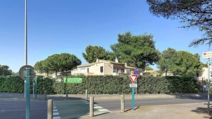 A residential area with a road sign indicating a no parking zone, a pedestrian crossing, and a green bike lane. - LA PINEDA 200m from the naturist village with parking space and swimming pool (Occitanie)