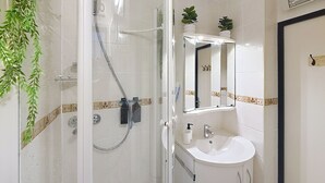 A bathroom with a glass-enclosed shower, a white sink, and a mirror above it. - LA PINEDA 200m from the naturist village with parking space and swimming pool (Occitanie)