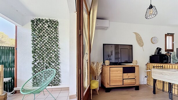 A living room with a TV, wooden cabinet, and a dining area. - LA PINEDA 200m from the naturist village with parking space and swimming pool (Occitanie)