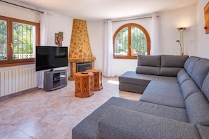 A living room with a television, sofa, fireplace, and large windows. - Villa Papillon by Villa Plus (Calp)
