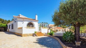 A white building with a tiled roof, a glass door, and a stone-paved entrance. - Villa Papillon by Villa Plus (Calp)