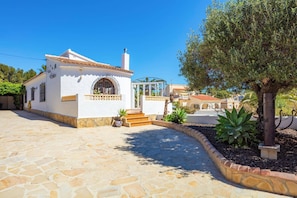 A white building with a tiled roof, a glass door, and a stone-paved entrance. - Villa Papillon by Villa Plus (Calp)