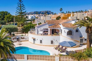 Une villa blanche dotée d’une piscine, d’un espace salon extérieur et offrant une vue sur le quartier environnant.