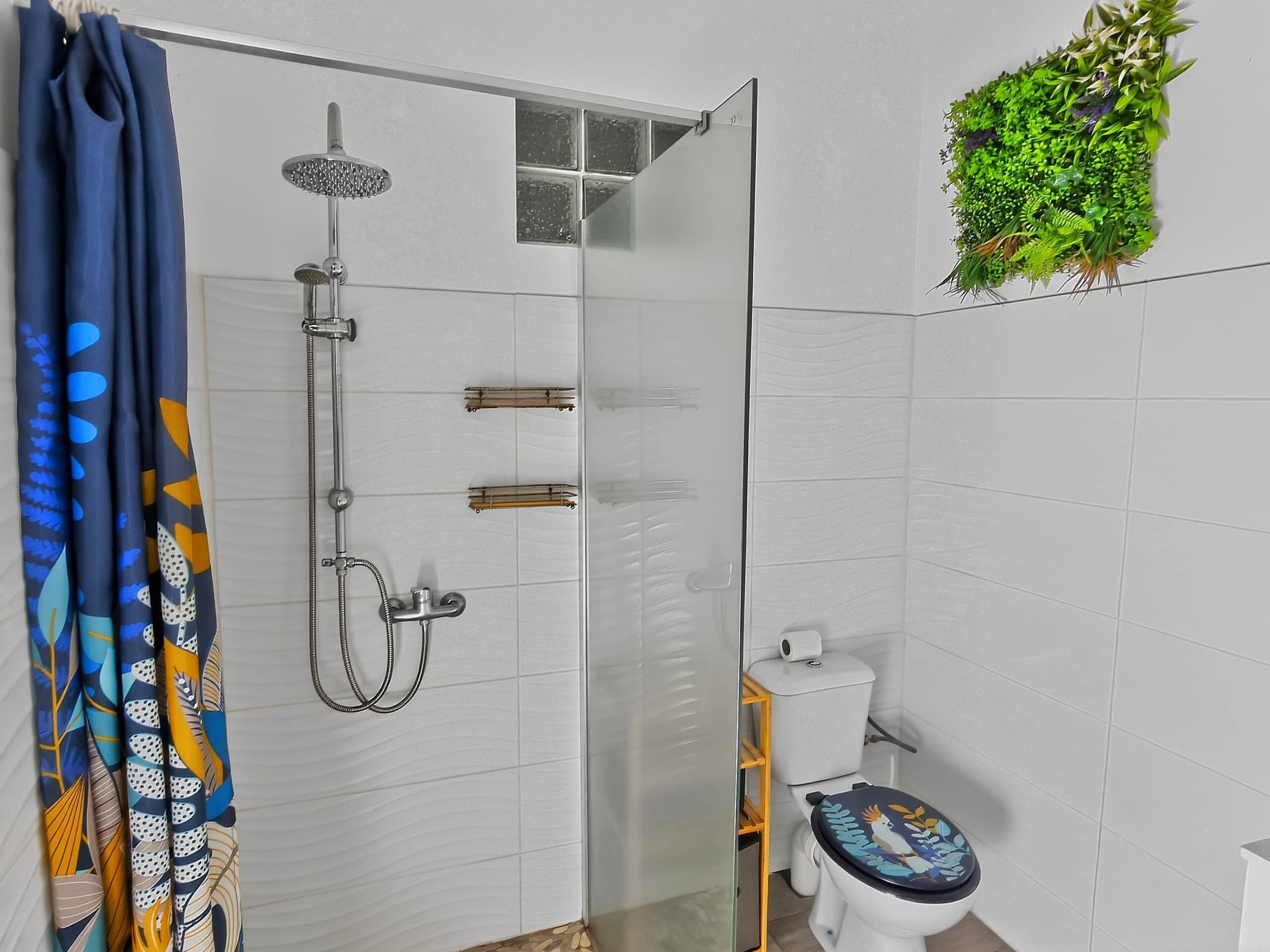 A bathroom with a glass-enclosed shower, a toilet with a decorative seat, and a wall-mounted plant.