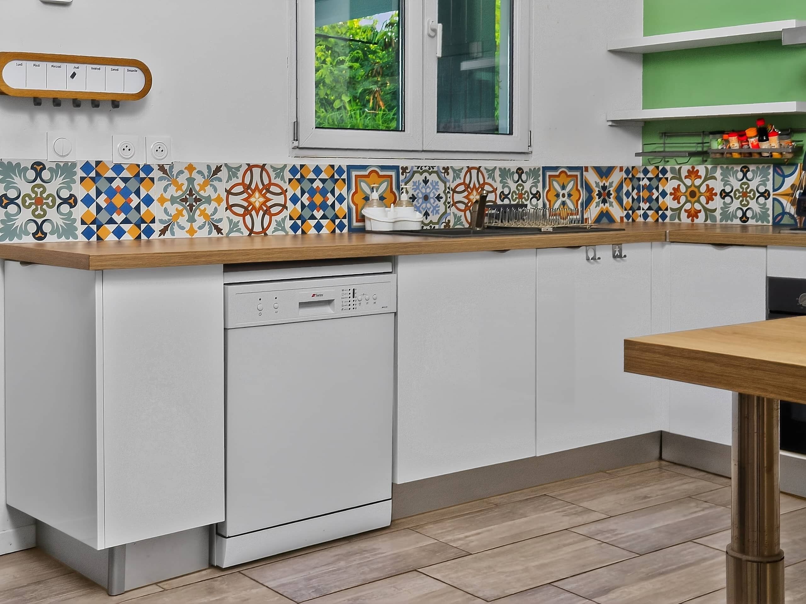 Una cocina con lavavajillas, ventana y salpicadero de azulejos.