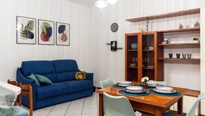 En matplats med ett träbord för fyra personer, en blå soffa och ett skåp med glasdörrar.