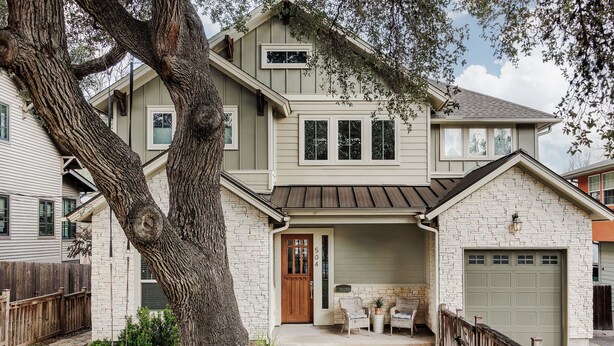 A two-story house with a stone facade, a front porch with chairs, and a garage. - SoCo Craftsman ~ Walk to Shops, Cafés, Parks (Austin)