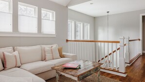 A living room with a sofa, a coffee table, and a staircase. - SoCo Craftsman ~ Walk to Shops, Cafés, Parks (Austin)