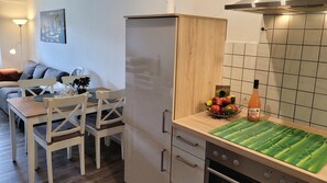 Una cocina compacta con refrigerador, un lavamanos y una encimera con un frutero y una botella.
