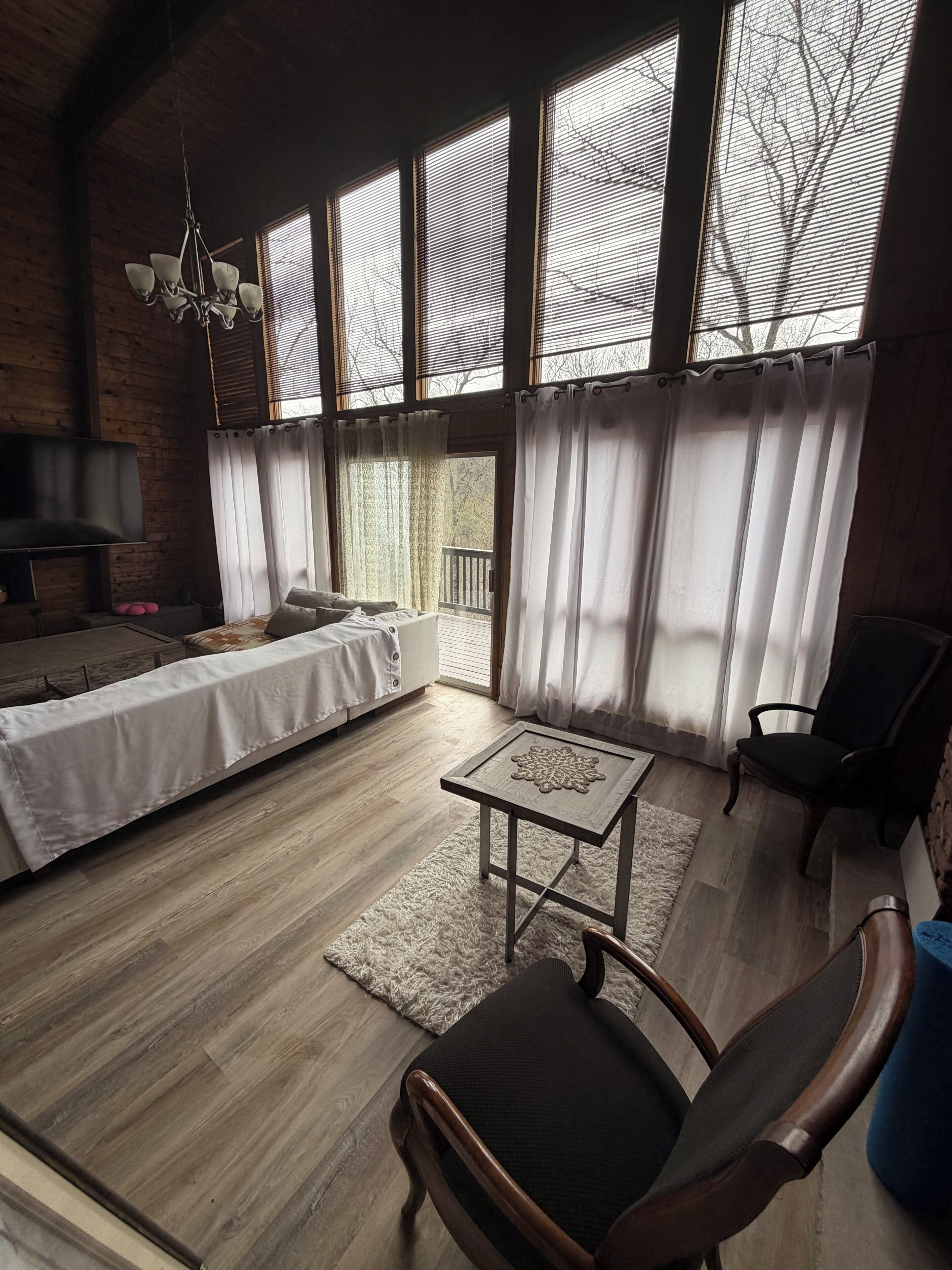 Um quarto espaçoso com cama, mesa, cadeira e janelas amplas.