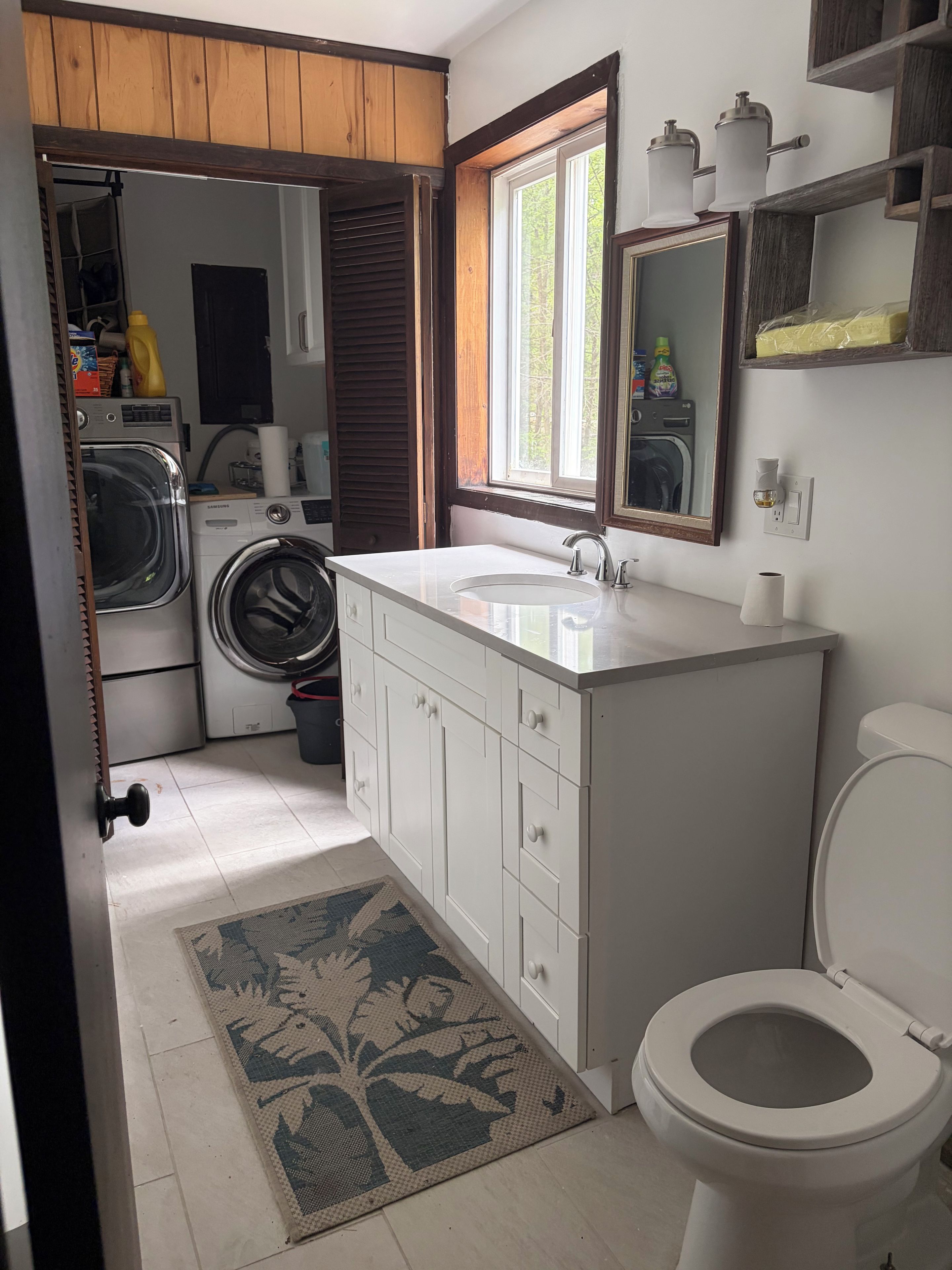 A compact bathroom with a washing machine, a sink, and a toilet.