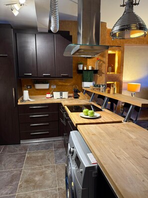 Eine moderne Küche mit dunklen Holzschränken, einer zentralen Kochinsel mit Spüle und Edelstahlgeräten.