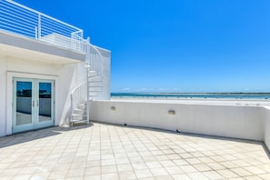 A rooftop terrace with a clear view of the beach, a white railing, and a spiral staircase. - Endless Views (St. Augustine)