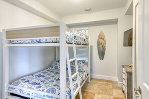 Ein Mehrbettzimmer mit einem Surfbrett an der Wand und einer Kommode.