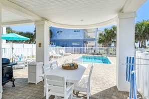 A covered patio with a pool, white furniture, and a view of a blue building. - Endless Views (St. Augustine)