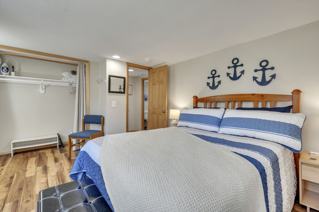 Une chambre à coucher comprenant un lit, une chaise, une armoire et une porte donnant sur une autre pièce.