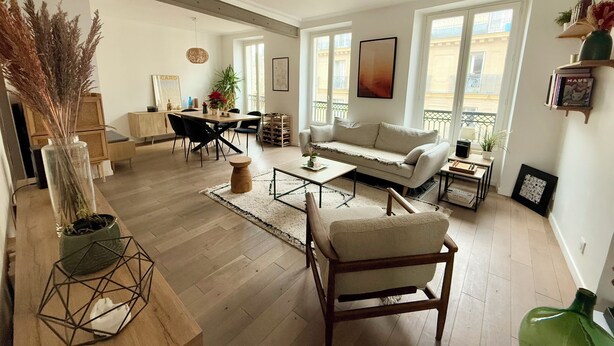 Ein geräumiges Wohnzimmer mit einer Couch, einem Essbereich und Blick ins Freie.