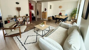 Ein geräumiger Wohnbereich mit Sofa, Couchtisch, Bücherregal und Esstisch.
