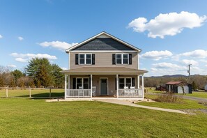 A two-story house with a front porch, a garage, and a small shed in the background. - Luxury Stay w/ Fenced Yard, Hot Tub, Mountain View (Afton)