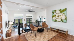 A spacious living area with a balcony, a ceiling fan, and a large floral painting on the wall. - Luxury Stay w/ Fenced Yard, Hot Tub, Mountain View (Afton)