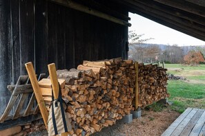 A stack of firewood outside a wooden building with a metal ladder and a bag leaning against it. - Luxury Stay w/ Fenced Yard, Hot Tub, Mountain View (Afton)