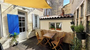 A patio with a table and chairs, a yellow umbrella, and potted plants. - Cocoon with garden in Bordeaux (Bordeaux)