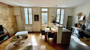 A compact living space with a dining area, a small kitchen, and a seating area with a sofa and a coffee table. - Cocoon with garden in Bordeaux (Bordeaux)