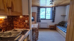 Interior compacto de una caravana con kitchenette, comedor y un espacio de estar acogedor.