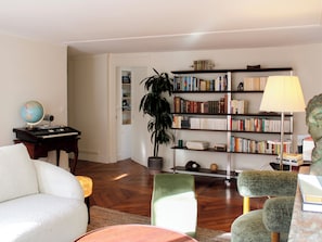 A living room with a bookshelf, a globe, a keyboard, and a lamp. - 96m² flat, overlooking Paris rooftops (Paris)