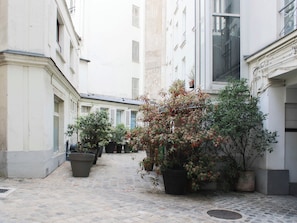A narrow cobblestone alley with potted plants and buildings on either side. - 96m² flat, overlooking Paris rooftops (Paris)