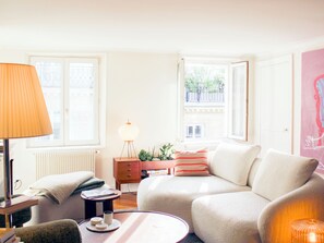 Un salon avec un canapé, une lampe, une petite table et un radiateur.