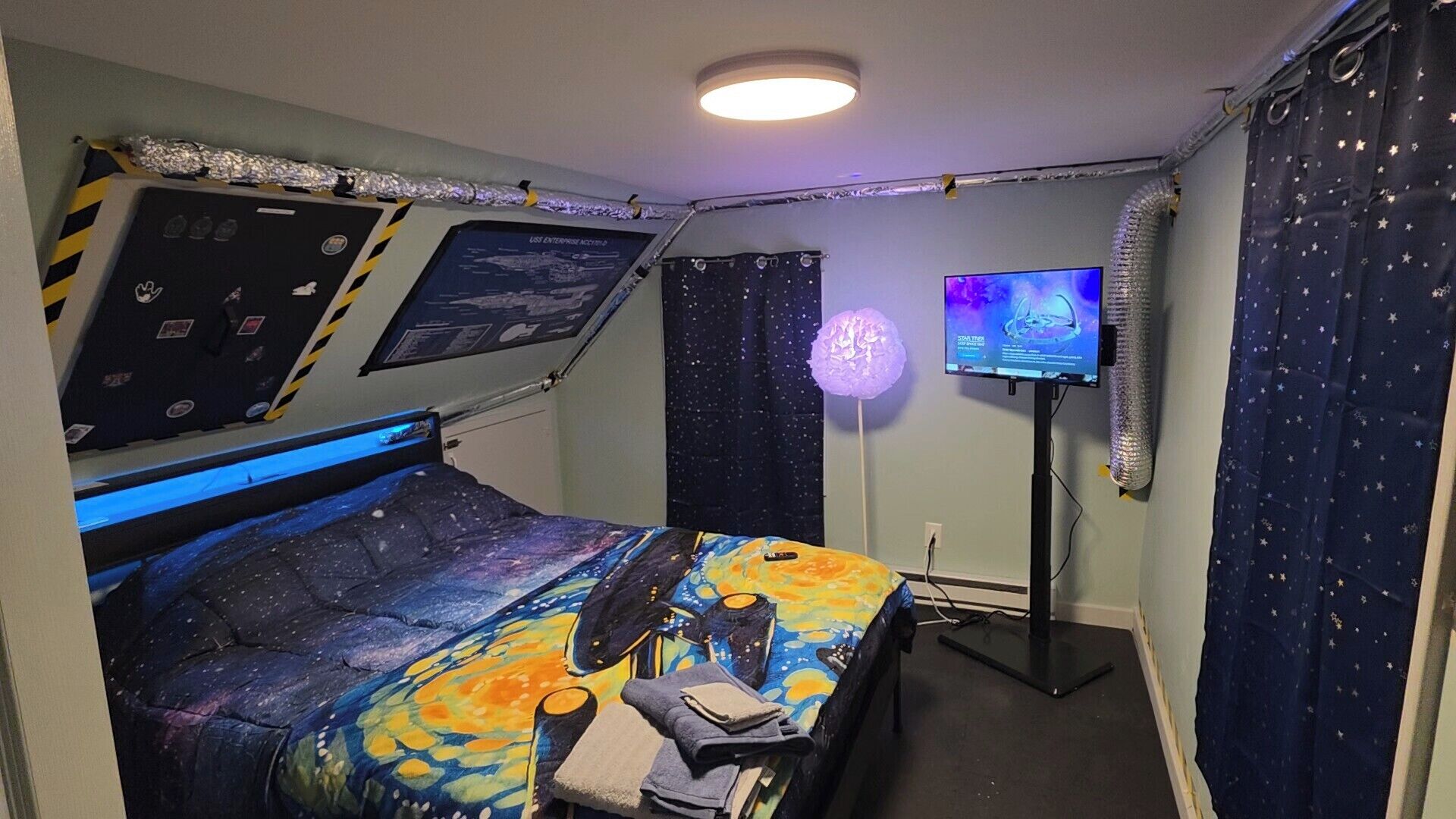 Een kamer met een bed, een tv aan de muur en een plafondventilator.