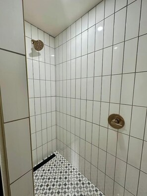 A small, tiled shower room with a white and black patterned floor.