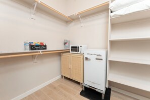 Eine kompakte Küchenzeile mit Mikrowelle, Kühlschrank, einer Speisekammer und einem Holzschrank.