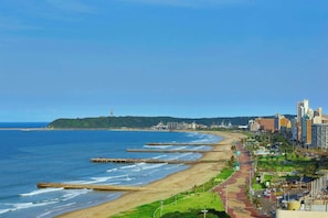 Un paysage urbain côtier avec une plage, une jetée et un mélange de bâtiments modernes et traditionnels.