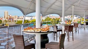A rooftop dining area with tables, chairs, and a city view. - Hilton Durban (Durban)