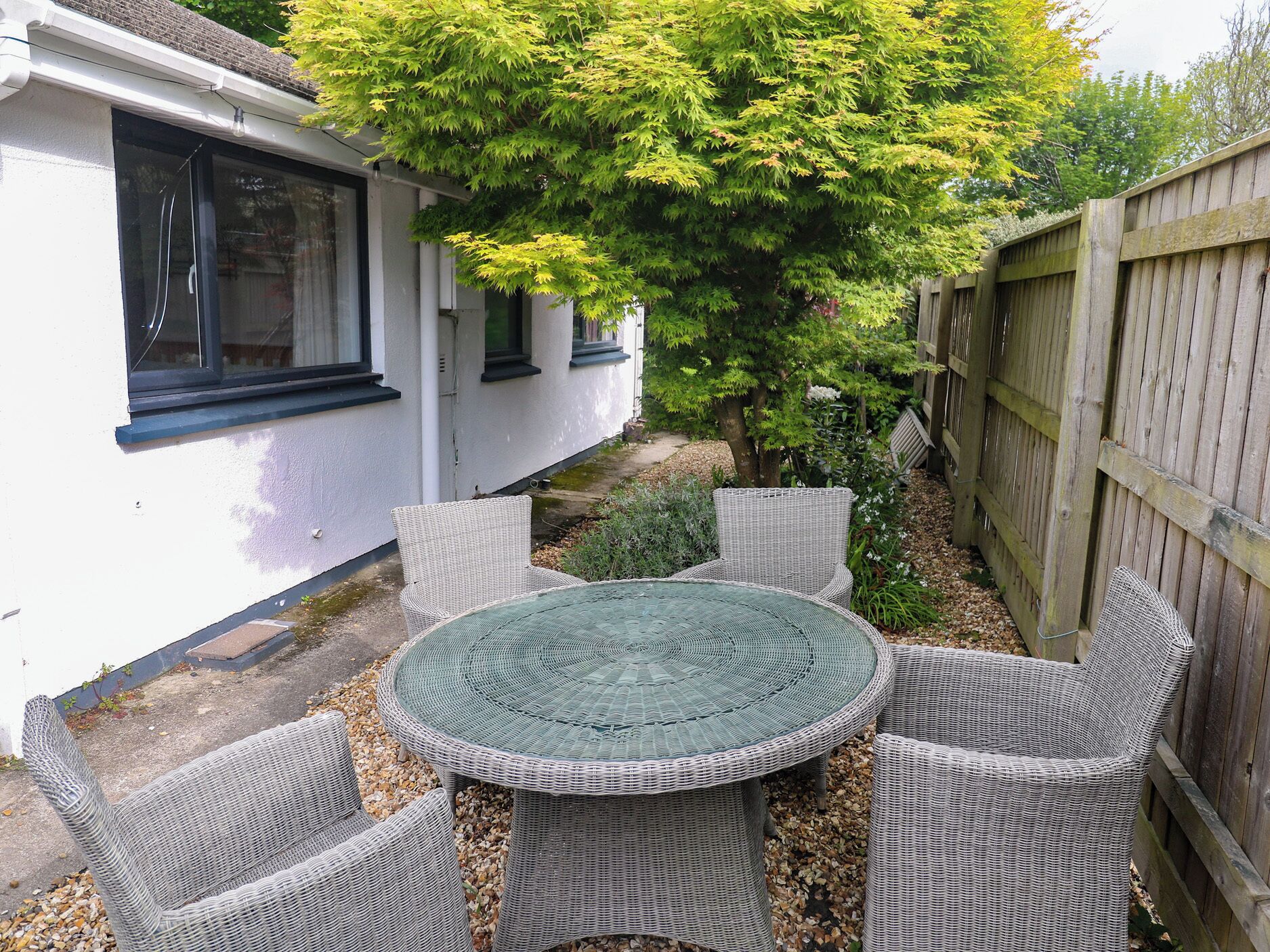 A patio with wicker furniture, a round table, and a wooden fence.