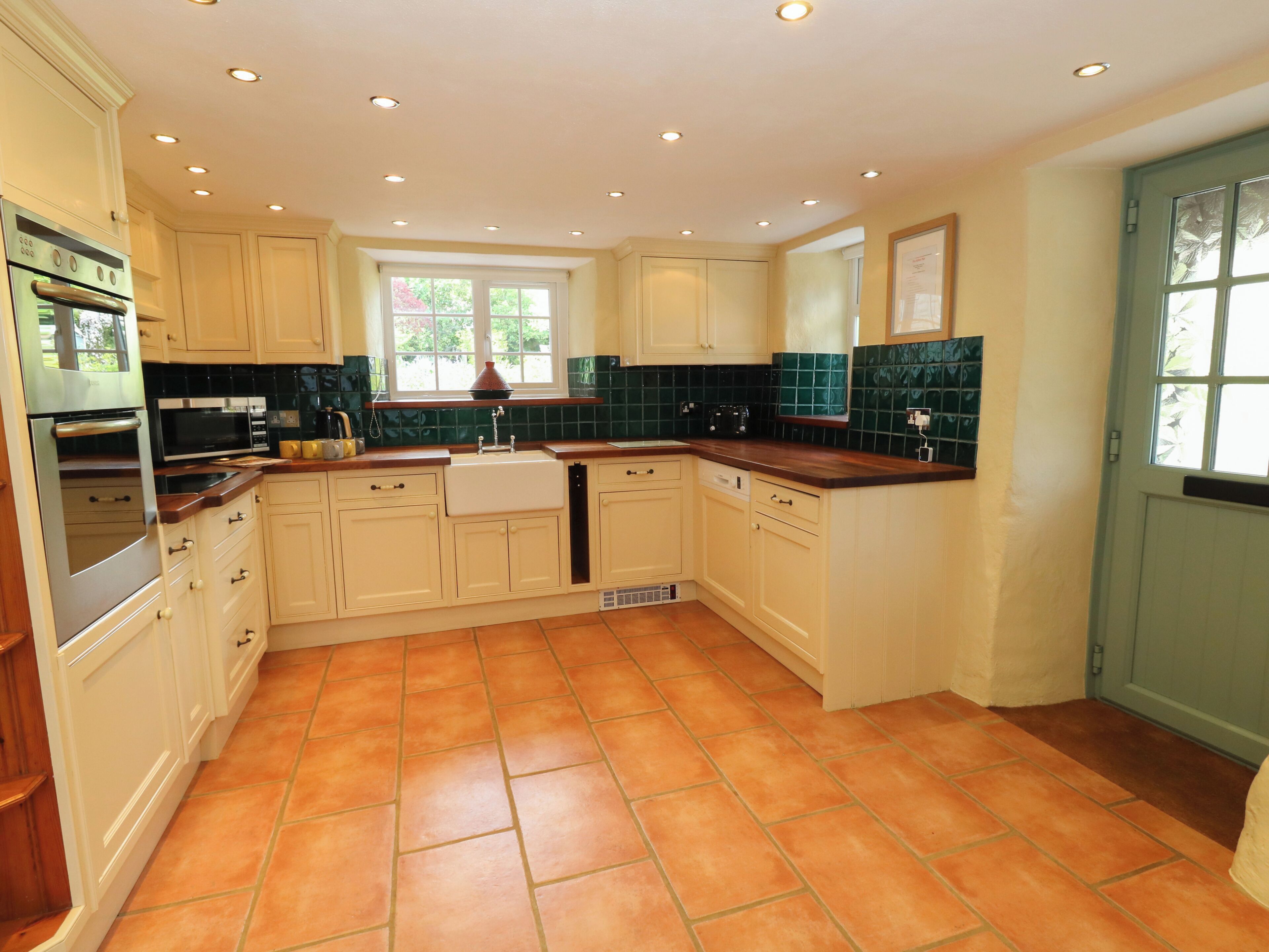 A kitchen with white cabinets, a tiled floor, and a window.