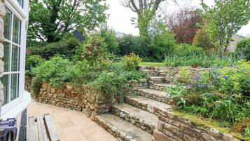 A stone staircase leading to a garden with various plants and flowers.