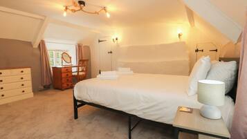 A bedroom with a bed, dresser, vanity, and a chandelier.
