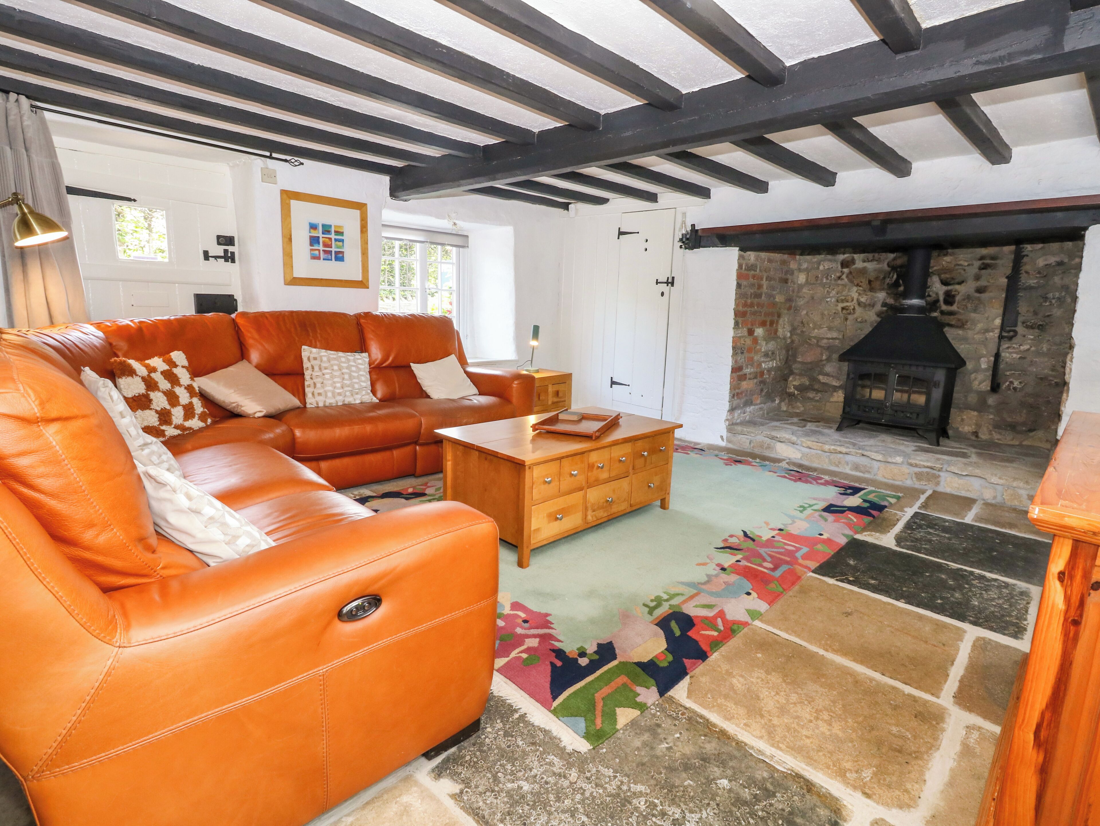 A cozy living room with a leather sofa, a wooden coffee table, and a stone fireplace.