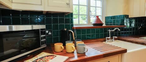 A kitchen with a microwave, a coffee maker, and a window with a view of greenery.