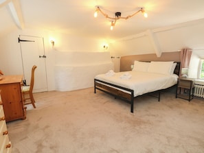 Un dormitorio con cama, mesita de noche, lámpara y una silla.