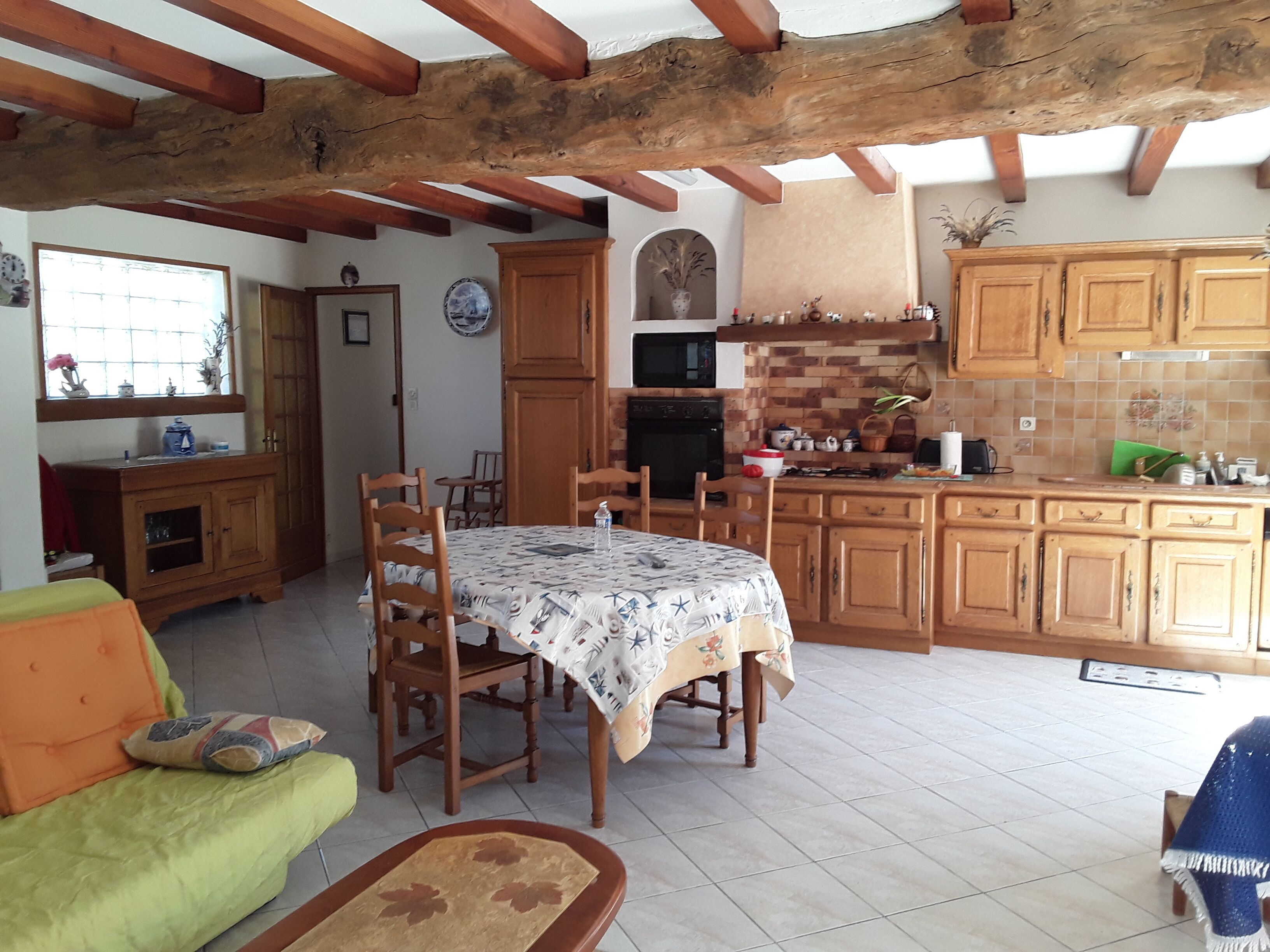 A spacious kitchen with wooden cabinets, a dining table with chairs, and a tiled floor.