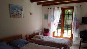 Een slaapkamer met twee bedden, een raam met gordijnen, een schilderij aan de muur en een radiator.